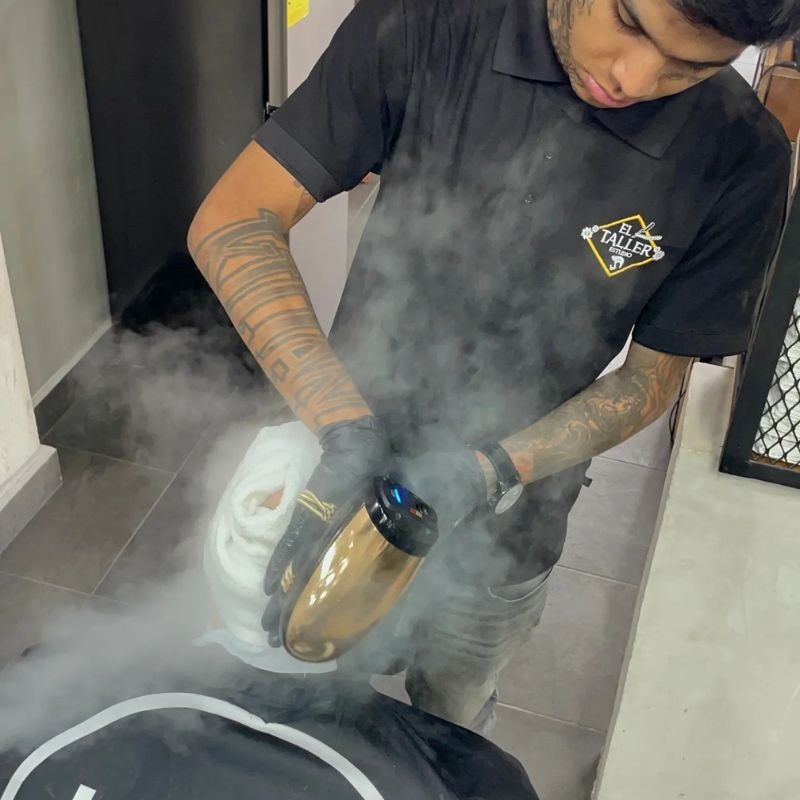 Barbero profesional utilizando vapor para desinfectar toallas en una barbería de Cancún.